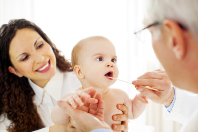 Baby with her mother having her mouth examined at doctor's office