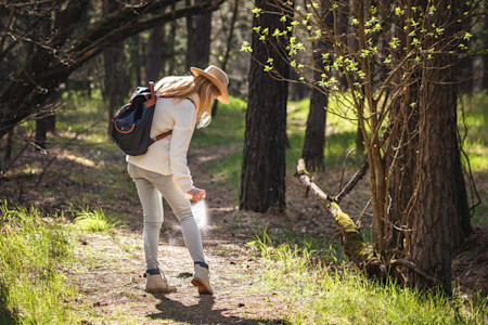 Woman spraying herself with tick repellent