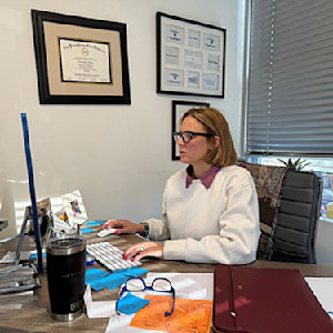 Card image of Emmy Graber, MD, MBA, FAAD, checking portal messages between patients at her practice in Boston. Photo courtesy of Dr. Graber.