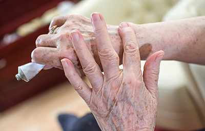Elderly woman applying cream to hands