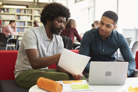 Two young Black men collaborating on paper about keloid scars