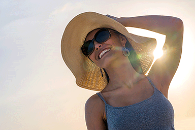 Woman wearing a wide-brimmed hat and sunglasses for sun protection.