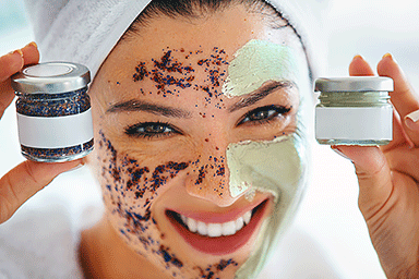 Young woman with clay mask and exfoliation cream on her face.