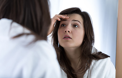 Woman examining acne