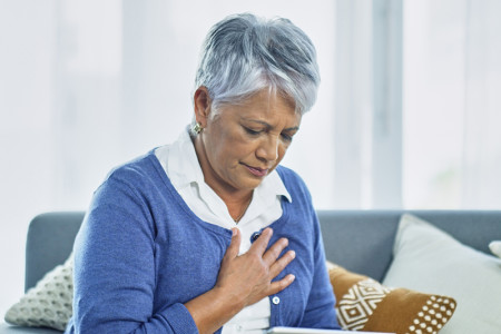 Mature woman holding her heart for an article about Rosacea and risk of heart attack.