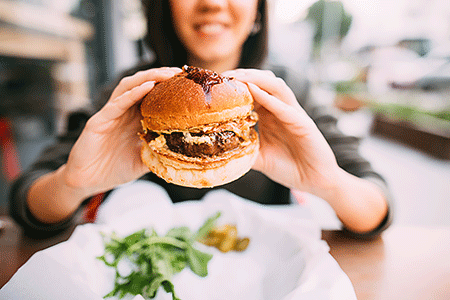 Woman about to bite into a hamburger.