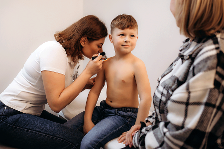 Dermatologist checking pityriasis rosea rash on child’s skin