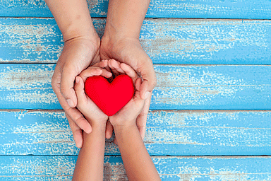 Red heart in child kid and mother hands on old blue wooden table background