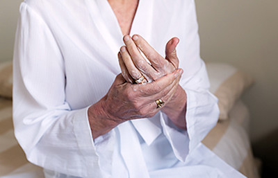 woman putting lotion on aging hands