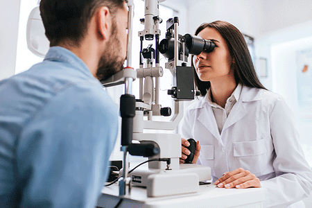 Female doctor ophthalmologist checking the eye vision of a young man.