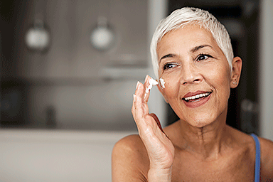 Senior woman applying anti-aging cream to her face.