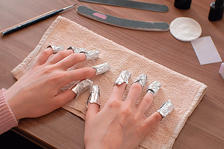 Người phụ nữ đeo giấy bạc quấn móng tay để loại bỏ bột nhúng màu móng tay