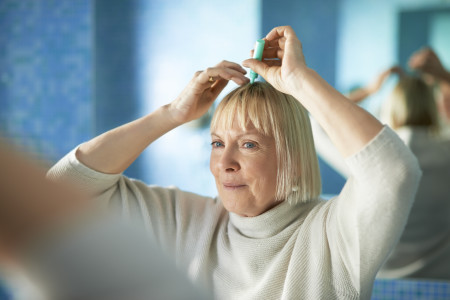 older woman applying ointment to scalp