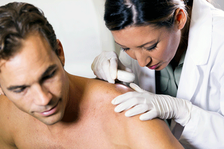 Dermatologist examining patient’s back for skin cancer