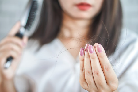 woman brushing hair and looking at loose hair