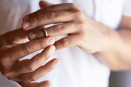 Close-up hands of male taking off his wedding ring