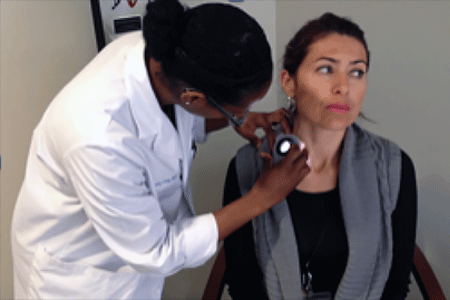 Dermatologist performing skin cancer screening on a woman