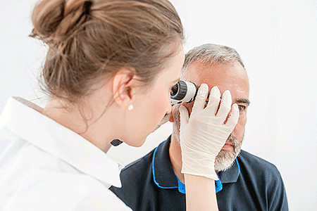 Dermatologist examining a man in his 50s for basal cell carcinoma on his face.