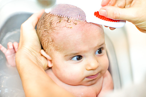Infant scalp being washed and combed