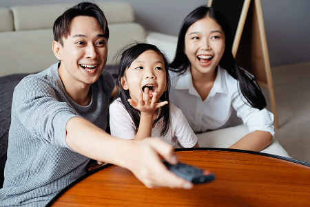 Mother, daughter, and father sitting close together and enjoying TV while the mother has pityriasis rosea.