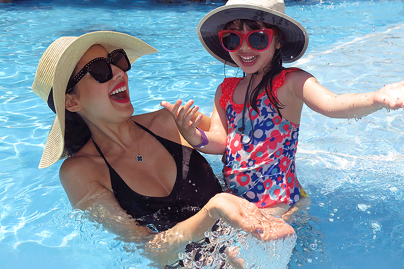 Mother and young daughter having fun in swimming pool.