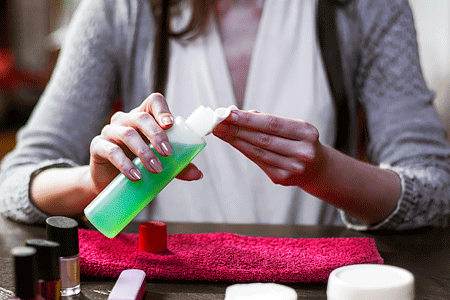 Woman's hands holding nail polish remover with towel on countertop