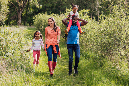 Happy family walking through woodland grass area