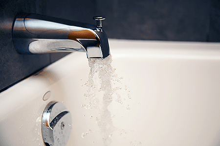 Close-up of running water pouring out of bathtub faucet