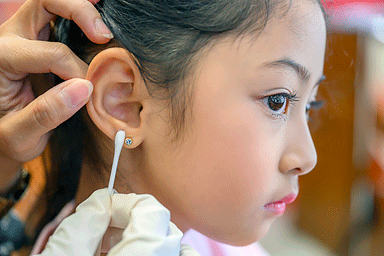 Young Asian girl having her ears pierced