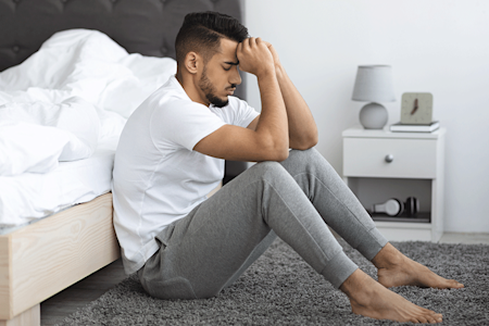 Patient with genital lichen planus sitting on floor in pain