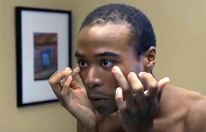 African American man gently washing face in mirror