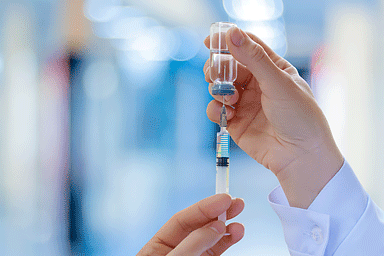 Doctor fills a syringe with a biologic treatment medication