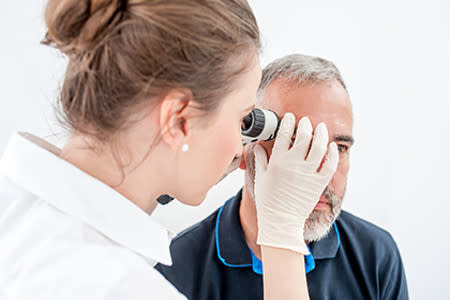 Woman dermatologist examining a patient's face for melanoma