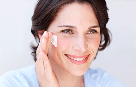 Woman applying cream to her face