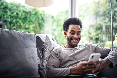 Man with Afro sitting on couch using his phone