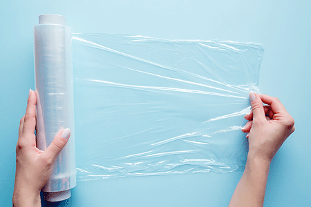 Woman's hand using a roll of plastic wrap