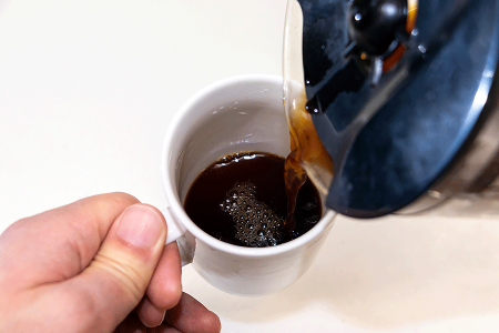 Man pouring coffee into a cup to find out if it triggers his hyperhidrosis