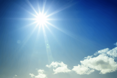 Bright sun shining in blue sky with starburst effect