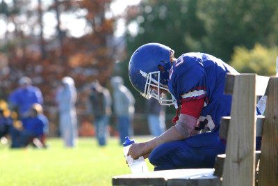 Football player sits on the sideline bench