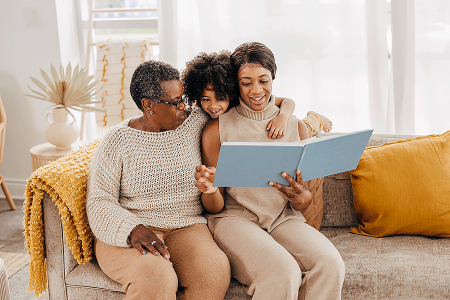 Three generations of a happy Black family reading a book
