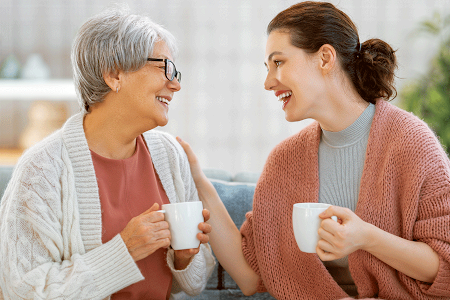 Mother with gray hair and daughter talking and smiling together