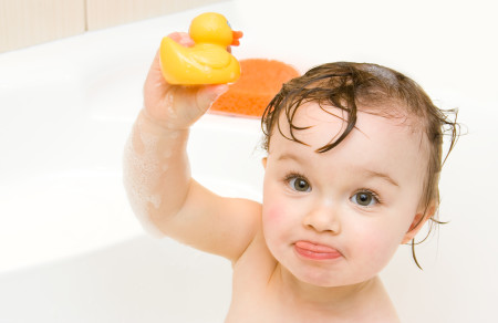 baby in tub holding rubber duck
