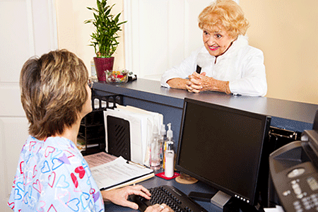 Woman at medical office speaking with receptionist at desk