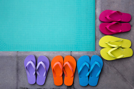 Brightly colored flip flops on edge of pool