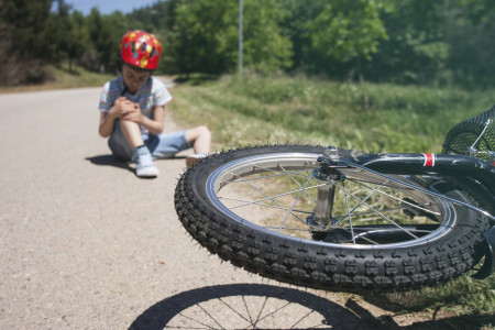 Boy sitting hurt on pavement after a bicycle accident 