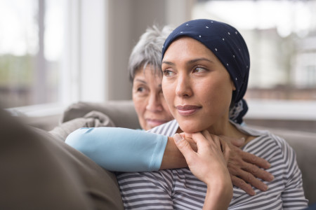 woman with scarf over head embraced by older woman