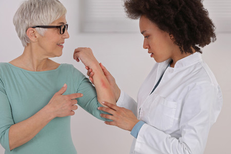 Dermatologist examining rash on patient’s arm