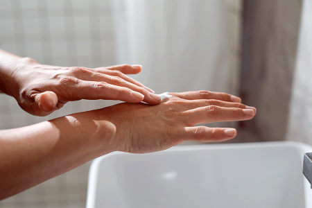 Woman with eczema applying hand cream in the bathroom