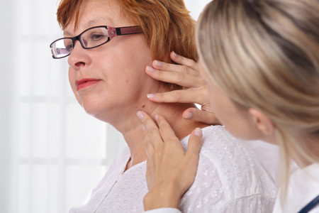 Dermatologist examining birthmark in elderly woman 