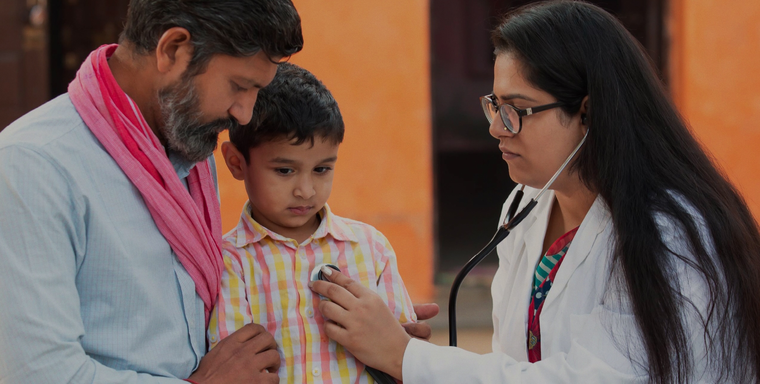 A doctor listening to the heart of a boy with his father
